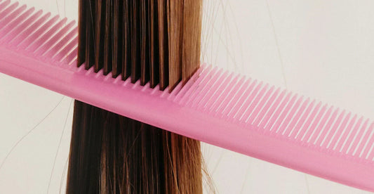 close up on hair with pink comb through it. 