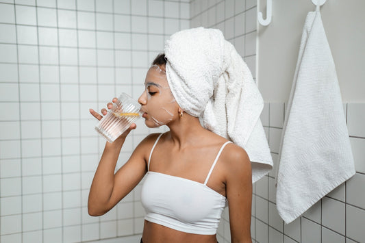en kvinna dricker vatten i badrummet