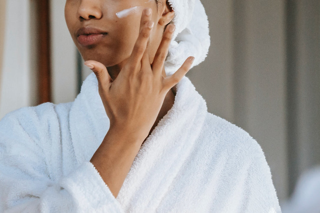 en kvinna applicerar ansiktskräm för att förbededa huden inför sommaren
