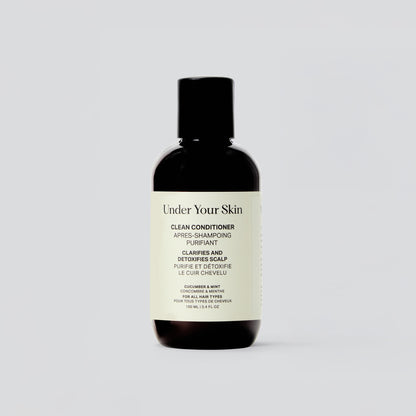 En ensam flaska av Under Your Skin Clean Conditioner står mot vit bakgrund. Etiketten visar att balsamet är veganskt och detoxar hårbotten.