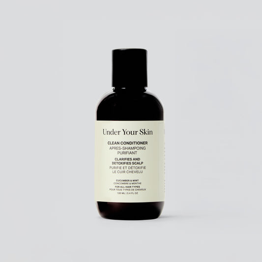 En ensam flaska av Under Your Skin Clean Conditioner står mot vit bakgrund. Etiketten visar att balsamet är veganskt och detoxar hårbotten.