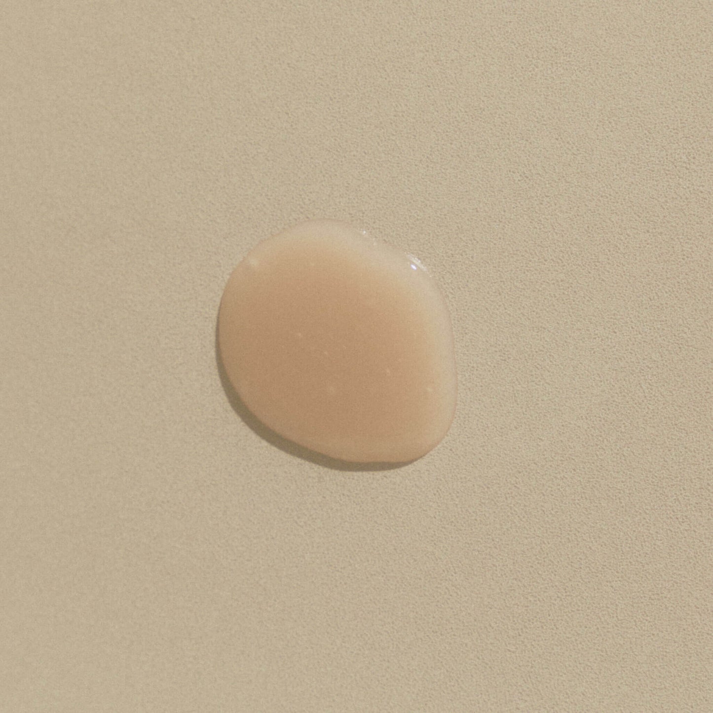Klar droppe schampo som visar textur på beige bakgrund