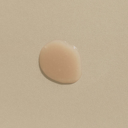 Klar droppe schampo som visar textur på beige bakgrund